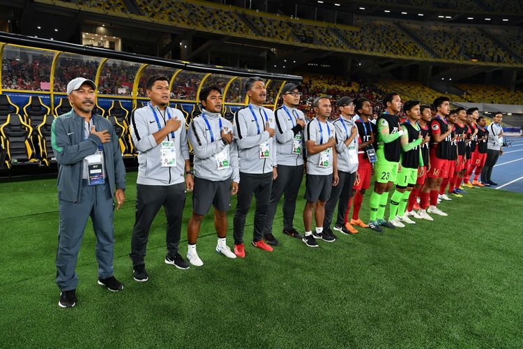 Pelatih Fakhri Husaini, staf pelatih Timnas U-16 Indonesia, dan para pemain cadangan menyanyikan lagu Indonesia Raya jelang laga versus Vietnam di Stadion Bukit Jalil, 24 September 2018. 