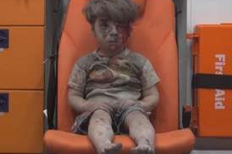 Omran Dagneesh (5) duduk termangu di dalam ambulans setelah selamat dari serangan udara pemerintah Suriah di kota Aleppo.