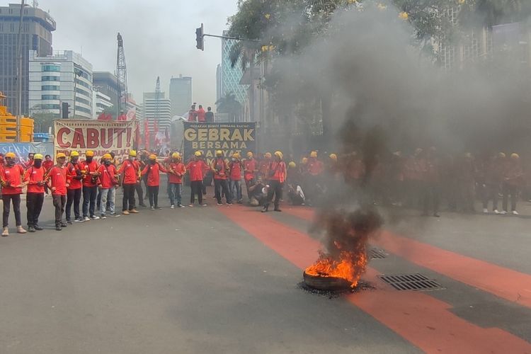 Sejumlah massa aksi buruh membakar flare dan ban saat demonstrasi menuntut Omnibus Law UU Cipta Kerja dicabut. Demonstrasi digelar di kawasan Patung Kuda, Jakarta Pusat, Senin (2/10/2023) siang.