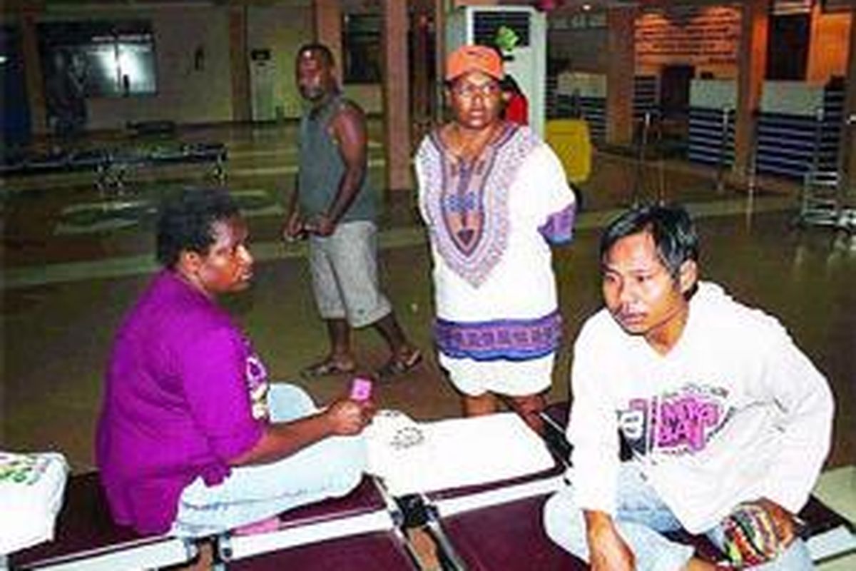Agustina Tekege (duduk, kiri) dan Seofrei Pakiding (kanan), keluarga penumpang pesawat, Minggu (2/8) di ruang check-in Bandara Sentani, Jayapura, Papua, menanti dengan cemas kabar ihwal Merpati tujuan Oksibil, Kabupaten Pegunungan Bintang, yang hilang kontak.