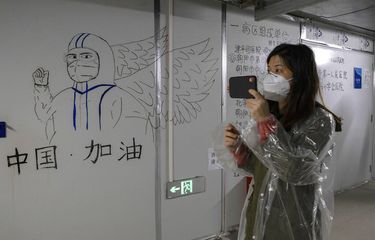 Seorang pengunjung melihat karya seni dengan tulisan Go China yang ditinggalkan oleh pekerja di Rumah Sakit Leishenshan yang dibangun di tempat parkir dari modul prefabrikasi dalam dua minggu di Wuhan di provinsi Hubei, China tengah, Sabtu, 11 April 2020.
