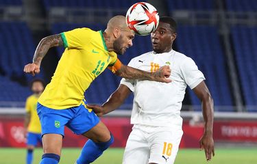 Pemain senior Brasil Dani Alves (kiri) berduel dengan gelandang Pantai Gading Cheick Timite (kanan) dalam laga lanjutan fase grup sepak bola putra Olimpiade Tokyo 2020 di Stadion Internasional Yokohama, Minggu (25/7/2021) sore WIB.
