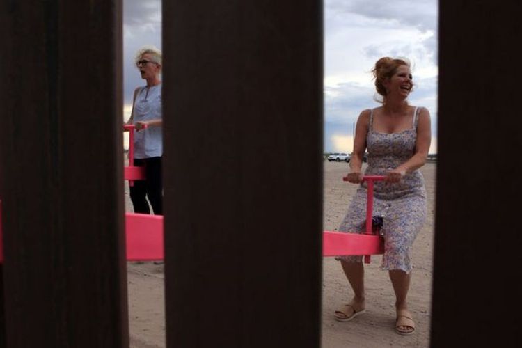Orangtua pun ikut bermain jungkat-jungkit pink di tembok perbatasan AS-Meksiko.
