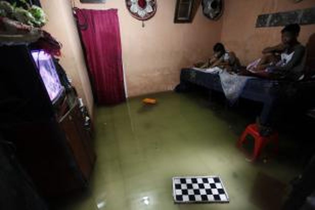 Yuni dan Iksan menyantap makanan di rumahnya yang tergenang banjir di Semper Barat, Cilincing, Jakarta Utara, Rabu (12/3/2014). Hujan deras mengakibatkan banjir setinggi hingga 50 sentimeter di kawasan tersebut sejak pagi. KOMPAS/LUCKY PRANSISKA