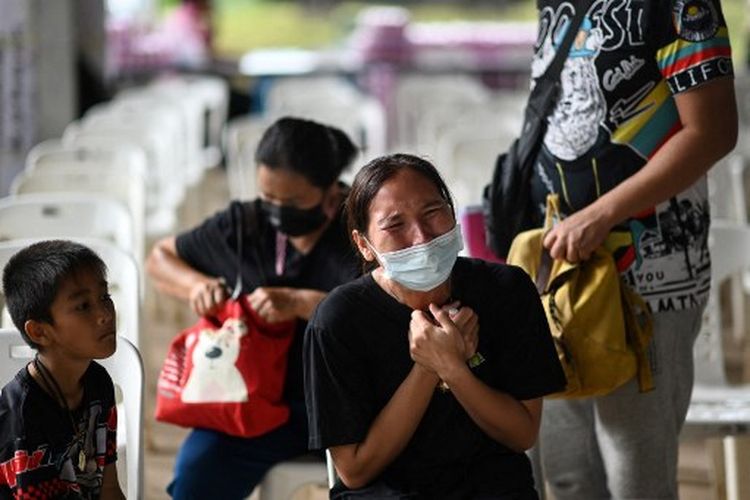 Seorang anak duduk di sebelah ibu korban saat dia menangis di luar kamar bayi, di mana seorang mantan polisi membunuh sedikitnya 37 orang dalam penembakan massal, di provinsi Nong Bua Lam Phu timur laut Thailand pada 7 Oktober 2022. Ini merupakan insiden penembakan massal Thailand terbesar oleh satu pelaku yang pernah terjadi di negara tersebut.