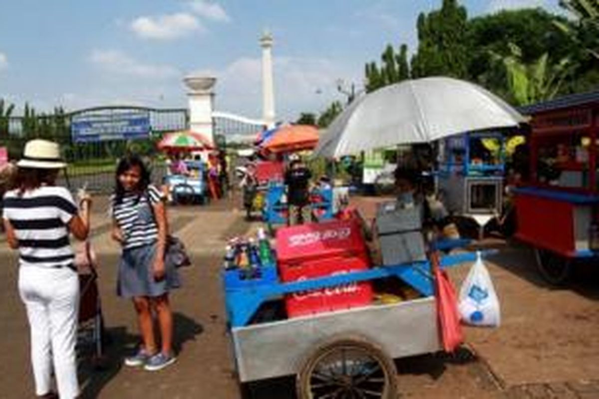 Pedagang kali lima dengan bebas menggelar dagangan di kawasan Monas yang dipenuhi orang yang berlibur seperti di Jalan Medan Merdeka, Gambir, Jakarta Pusat, Selasa (29/7/2014). Mereka tidak memedulikan larangan berdagangan di sekitar Monas. 