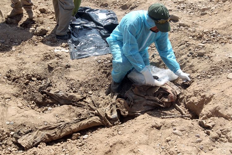 Foto yang diambil pada 2015, menunjukkan petugas keamanan Irak memeriksa jenazah yang ada di salah satu kuburan massal yang ditemukan di kota Tikrit.