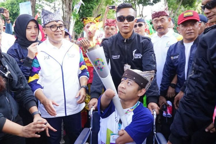 Dzoel, fotografer difabel yang membawa obor Asian Games saat melintas di Kota Banyuwangi, Minggu (22/7/2018).