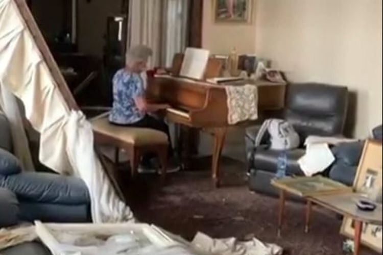 Seorang nenek memainkan piano di rumahnya yang porak poranda akibat ledakan di Beirut.