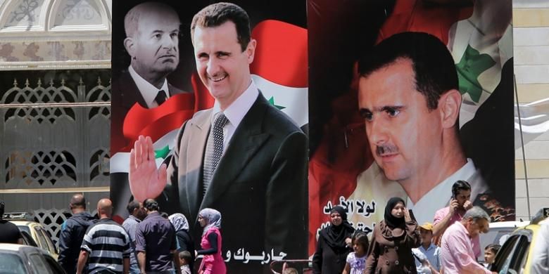 Warga Damaskus berjalan melewati poster raksasa Bashar al-Assad yang maju dalam pemilihan presiden yang digelar, Selasa (3/6/2014). 