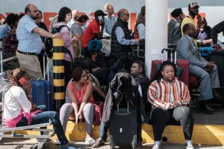 Penumpang menunggu di pintu masuk terminal keberangkatan selama aksi mogok pekerja bandara di Bandara Internasional Jomo Kenyatta di Nairobi, Kenya, Rabu (6/3/2019). (AFP/YASUYOSHI CHIBA)