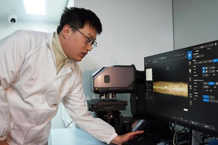 Seorang peneliti menunjukkan gambar cip serat yang diperbesar di sebuah layar komputer di Universitas Fudan di Shanghai, China timur, pada 19 Januari 2026.