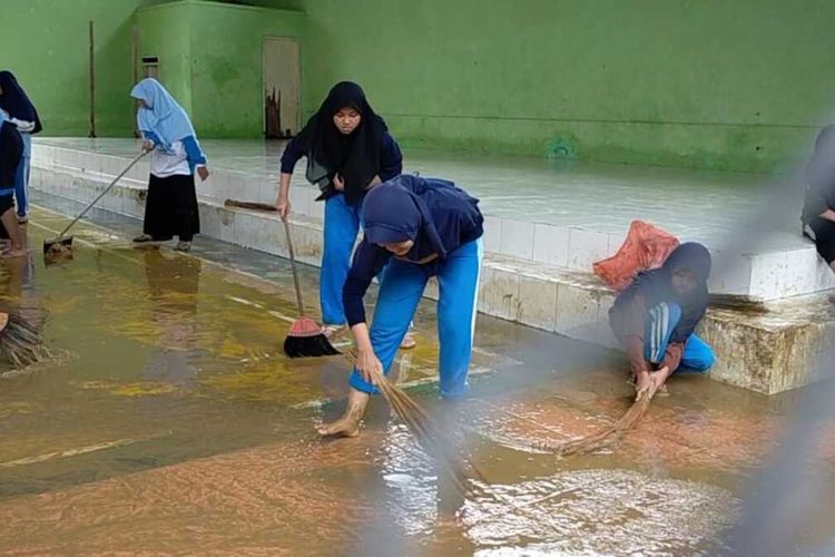 Siswa dan siswi SMPN 1 Pamekasan, Jawa Timur membersihkan sekolahnya, Senin (24/2/2020) karena terendam lumpur akibat banjir yang terjadi pada Sabtu (22/2/2020) kemarin. Pelajaran kelas diganti menjadi kerja bakti.