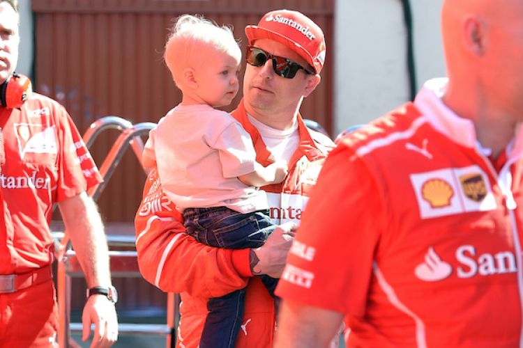 Pebalap Ferrari asal Finlandia, Kimi Raikkonen (tengah), menggendong anaknya, Robin, saat berjalan di Circuit de Barcelona-Catalunya pada hari keempat tes pramusim kedua Formula 1 2017, Jumat (10/3/2017).