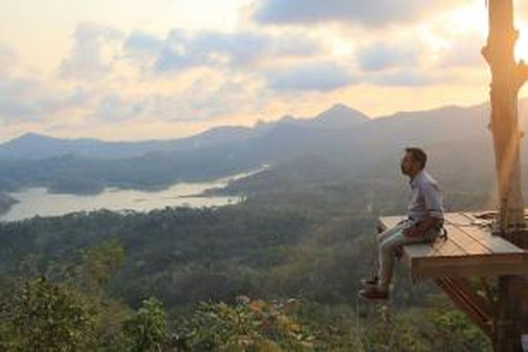 Pengunjung menjajal sensasi berfoto di menara pandang di atas pohon (spot foto), Kamis (8/10/2015). Terlihat dalam latar foto itu Waduk Sermo, perbukitan Menoreh, serta Gunung Susukan dan Gunung Ijo. 