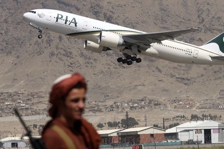 Dalam file foto ini seorang pejuang Taliban berjaga-jaga saat pesawat Pakistan International Airlines, penerbangan internasional komersial pertama yang mendarat sejak Taliban merebut kembali kekuasaan bulan lalu, lepas landas dengan penumpang di bandara di Kabul pada 13 September 2021. 