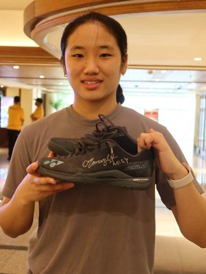 Pebulu tangkis tunggal putri asal Korea Selatan, An Seyoung, menunjukkan sepatu miliknya yang akan dilelang di acara Badminton Charity for Bali.