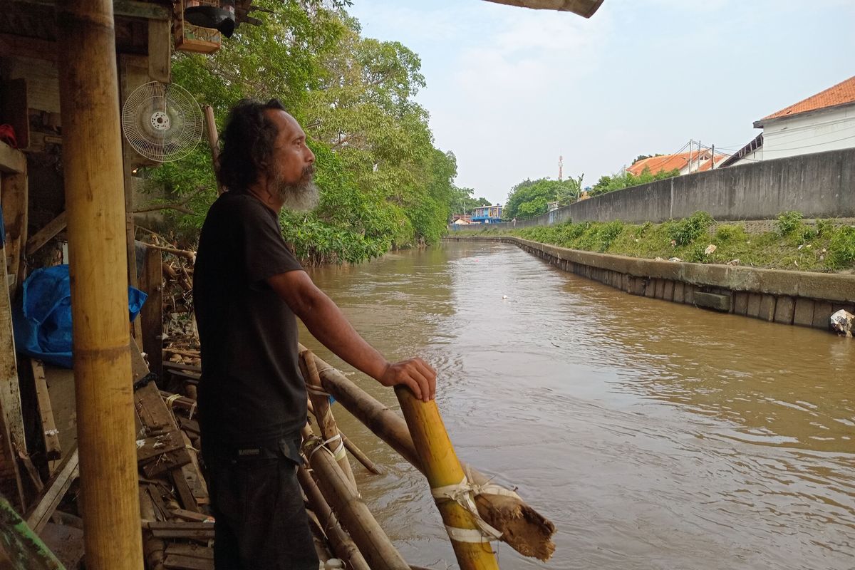 Seorang warga di permukiman Kebon Pala II, Jatinegara, Jakarta Timur, sedang memerhatikan aliran air Kali Ciliwung yang tak jauh dari tempat tinggalnya, Minggu (26/5/2024).