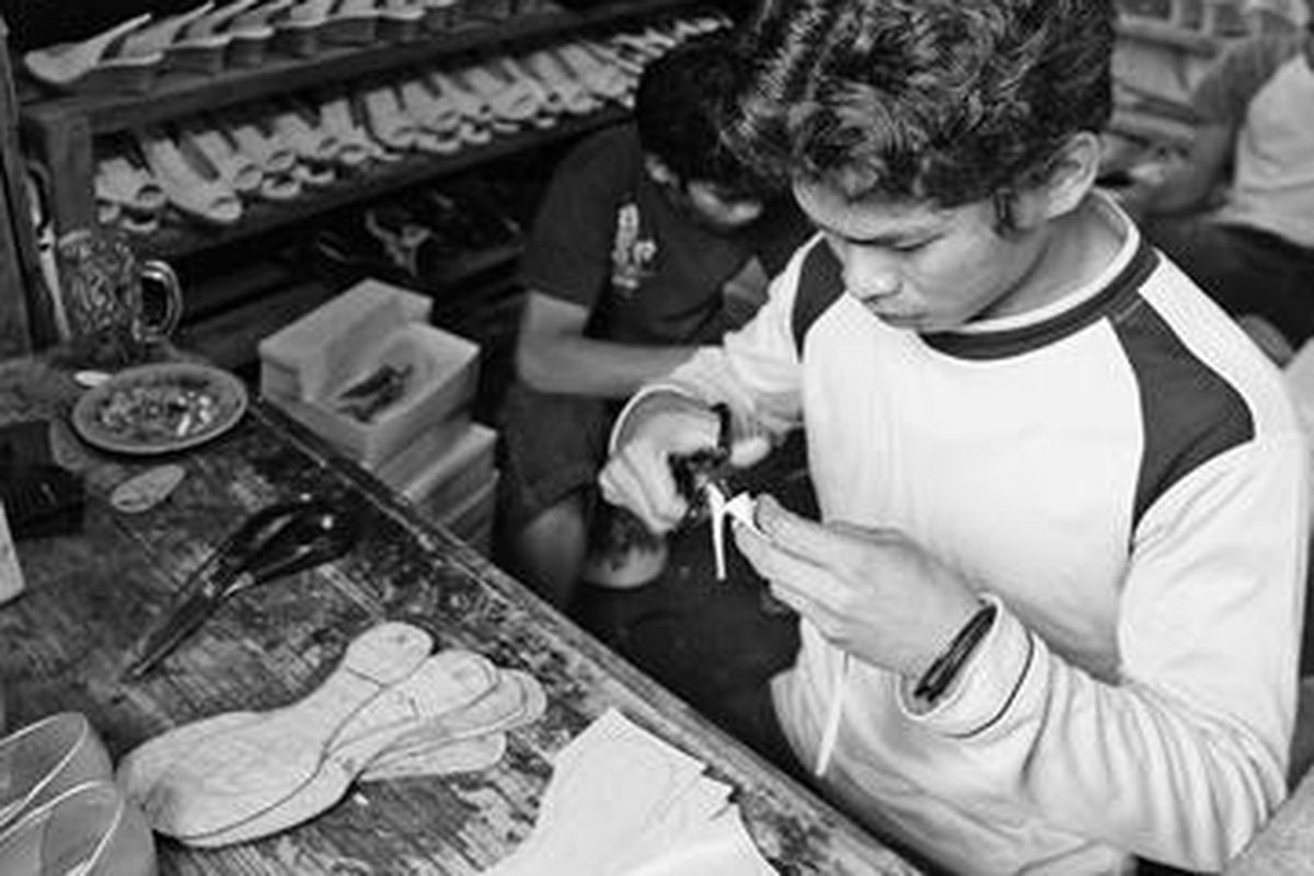 Perajin sandal wanita di bengkel produksi di kawasan Mampang, Jakarta, Rabu (27/2). Produsen sandal lokal ini berusaha bertahan di tengah arus deras produk serupa dari China yang dijual dengan harga murah.  