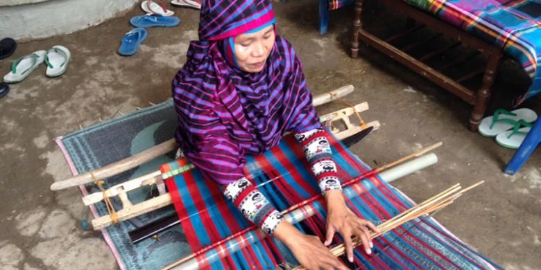 Warga Bima, Andriyani (36), sedang mengerjakan kain tenun Mbojo di halaman rumahnya yang berada di Kampung Cempaka Indah, Kota Bima, Nusa Tenggara Barat, Selasa (9/6/2015). 