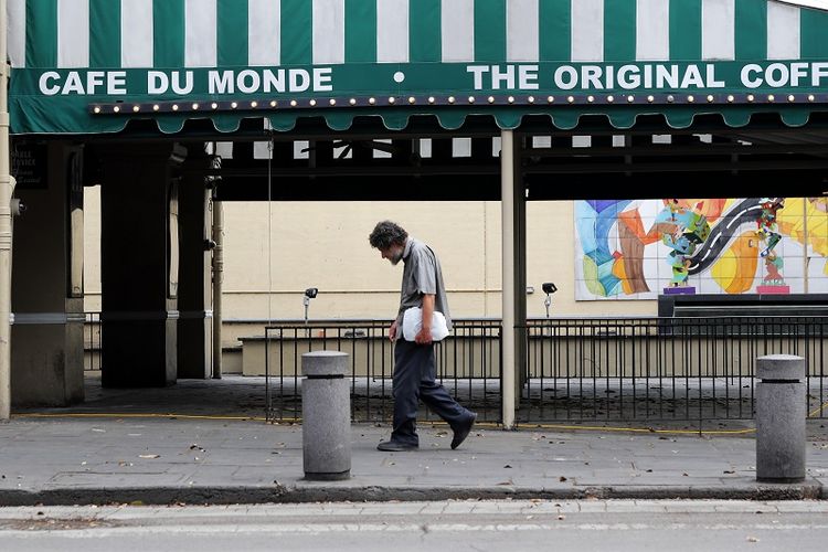 Pada Jumat, 27 Maret 2020 file foto ini menunjukkan seorang pria berjalan melewati restoran Cafe Du Monde yang tutup di French Quarter di New Orleans. Presiden AS terpilih Joe Biden akan mewarisi ekonomi AS yang hancur, ekonomi yang tidak pernah sepenuhnya sembuh dari virus korona dan dapat menderita lagi saat infeksi baru meningkat.