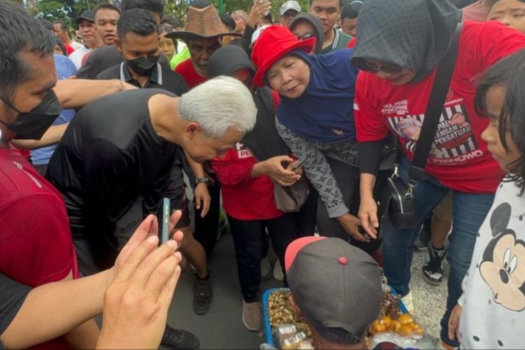 Momen Ganjar Pranowo membeli pisang rebus pedagang kakii lima saat melakukan kegiatan car free day di Kota Mataram, Minggu (3/12/2023)