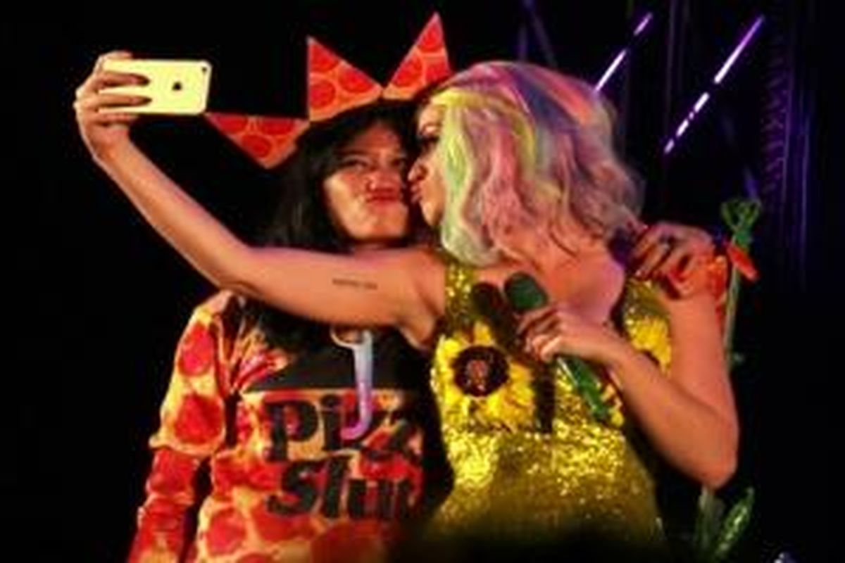 Katy Perry saat mengajak salah satu penonton untuk selfie di atas panggung.