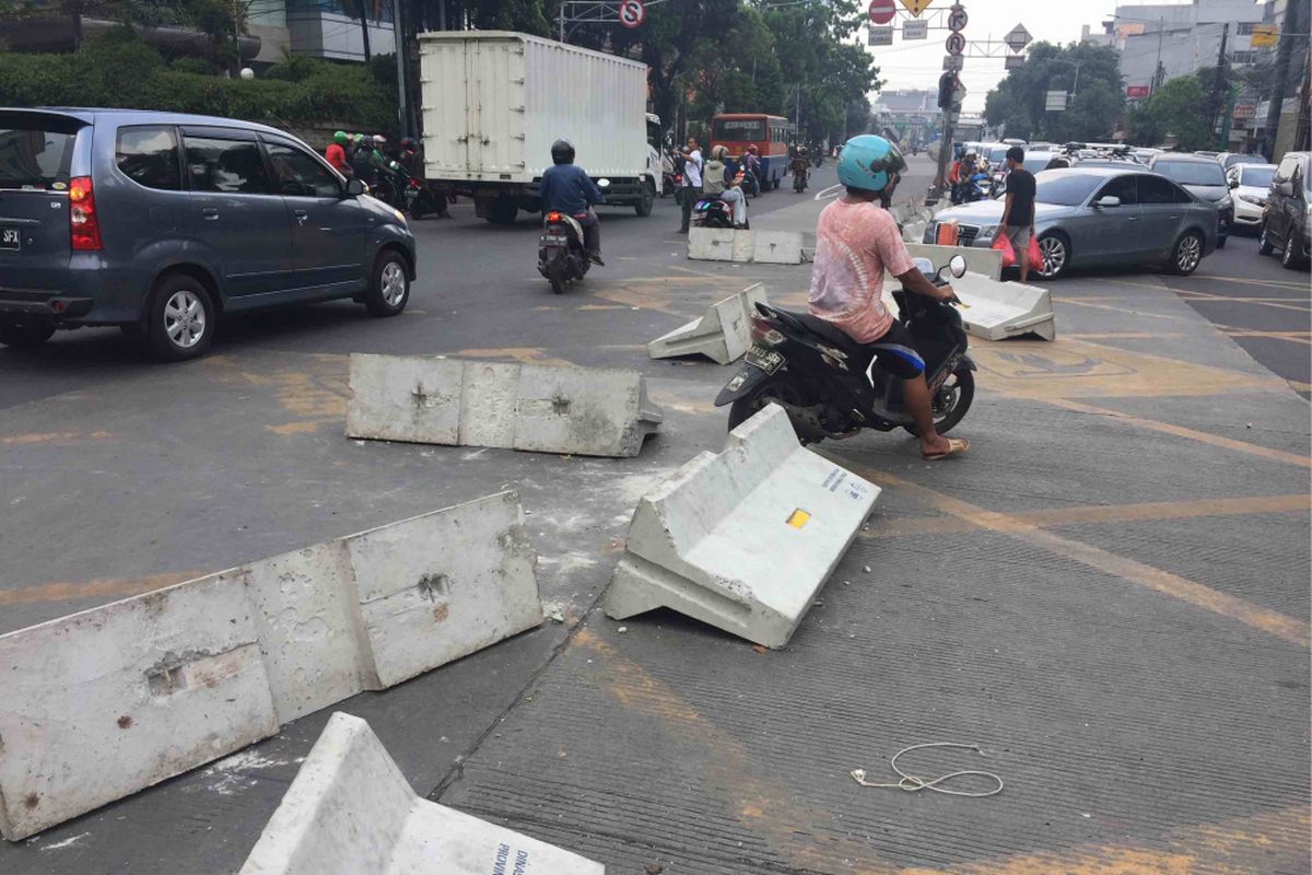 Puluhan warga dibantu pengendara yang melintas membongkar pembatas jalan di Simpang Duren Tiga, Kelurahan Duren Tiga, Kecamatan Pancoran, Jakarta Selatan, Sabtu (19/5/2018). Adapun pembatas jalan tersebut dipasang sebagai bagian uji coba penutupan simpang untuk memperlancar arus lalu lintas pasca-beroperasinya lintas bawah atau underpassMampang-Kuningan.