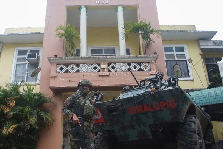 Seorang anggota polisi Pasukan Aksi Khusus (SAF) bersenjata berjaga di depan balai kota di kota Pamplona di Negros Oriental pada 5 Maret 2023, sehari setelah gubernur provinsi Roel Degamo dan delapan orang lainnya tewas dalam penembakan massal.