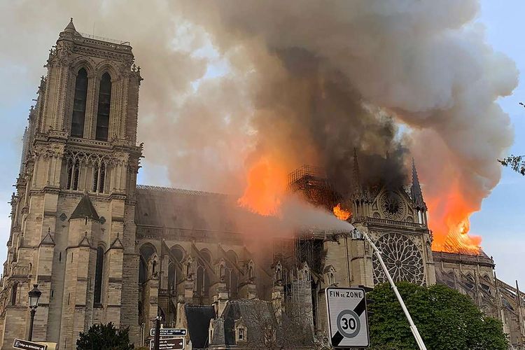 Api membakar bagian atas Gereja Notre Dame di Paris, Perancis, pada Senin (15/4/2019). Belum diketahui penyebab pasti kebakaran itu, api dengan cepat melalap atap dan puncak menara gereja bernuansa Gotik yang dibangun pada abad ke-12 itu.