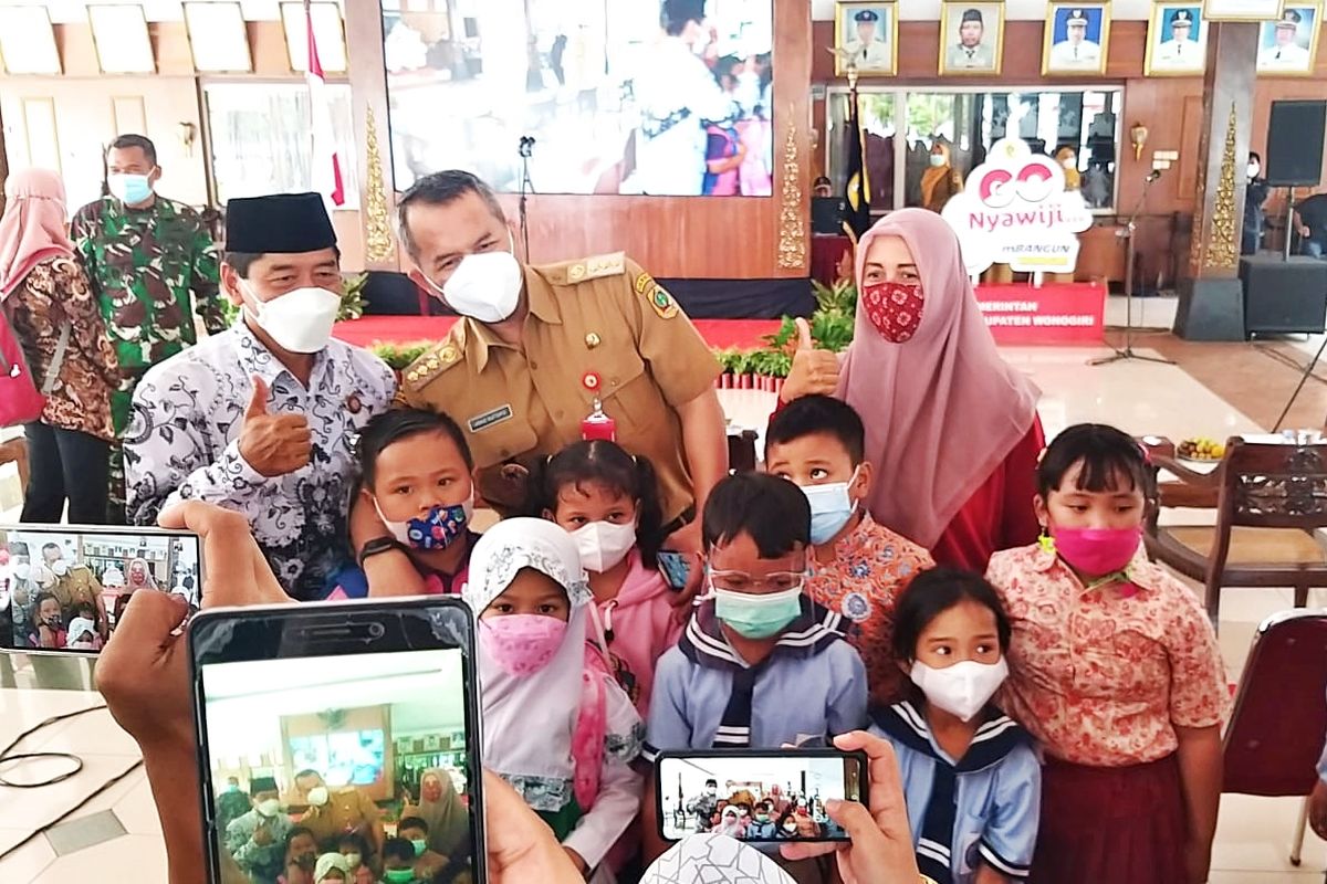 Bupati Wonogiri Joko Sutopo berfoto bersama anak-anak sekolah yang menerima bantuan seragam gratis di Pendopo Pemkab Wonogiri, Senin (15/11/2021). Pemkab Wonogiri membagikan 21.000 seragam gratis bagi siswa baru SD dan SMP di seluruh sekolah di 25 kecamatan.