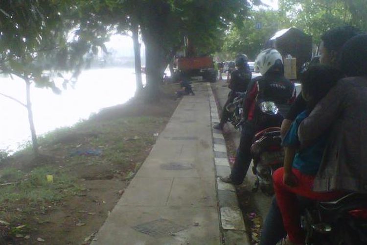 Kondisi trotoar Danau Sunter Selatan, Jakarta Utara tahun 2013. Saat itu para pengendara motor menikmati atraksi dari mesin eksavator yang sedang menguruk lumpur di danau tersebut.