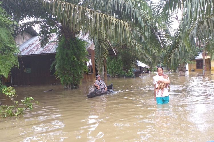 Seorang ibu menggendong bayinya melintasi genangan banjir di Desa Buluh Cina, Kecamatan Siak Hulu, Kabupaten Kampar, Riau, Kamis (26/12/2019). Warga mengeluhkan beberapa macam penyakit, seperti gatal-gatal dan cacar air akibat banjir yang bercampur dengan lumpur.