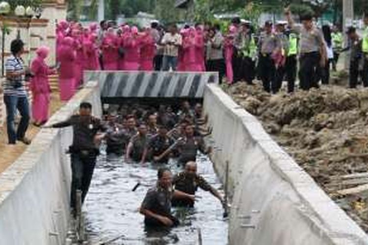 Puluhan istri polisi menyaksikan dan memotret suami mereka saat berenang di parit selokan depan Mapolres Aceh Utara, Sabtu (31/12/2016). 