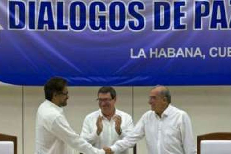 Menteri Luar Negeri Kuba, Bruno Rodriquez (tengah) menyaksikan negosiator pemerintah Kolombia, Humberto de la Calle (kanan) dan juru runding FARC Ivan Marquez (kiri) menandatangani kesepakatan damai di Havana, Kuba.