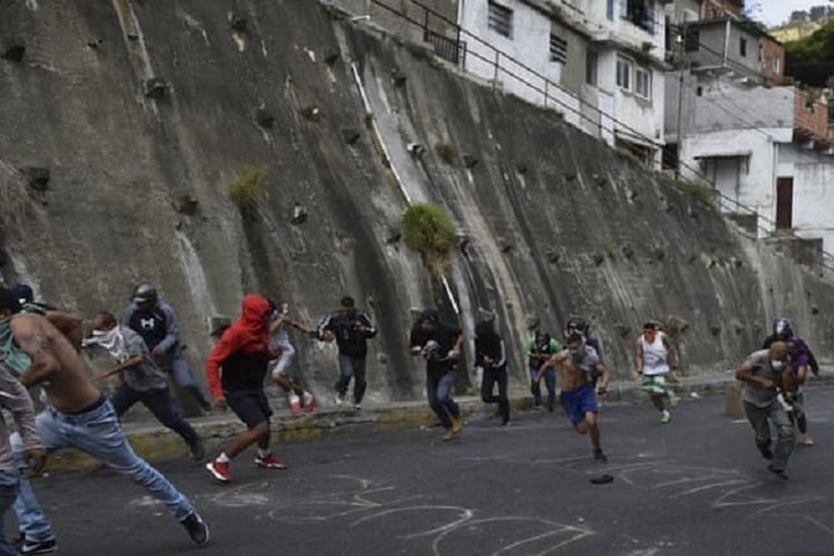 Massa anti-pemerintah Venezuela ketika terlibat bentrokan dengan polisi di Cotiza, utara Caracas, pada Minggu (21/1/2019).