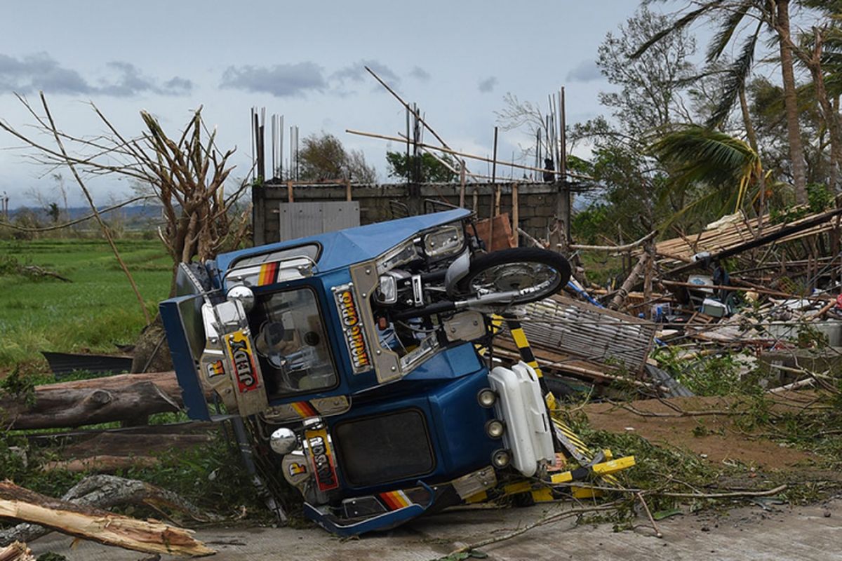 Sebuah kendaraan roda tiga yang terbalik terlihat di samping rumah yang hancur setelah Topan Mangkhut mengantam Kota Alcala, provinsi Cagayan, Sabtu (15/9/2018). Topan Mangkhut terus bergerak menerjang China selatan setelah sebelumnya menewaskan sedikitnya 64 orang di Filipina dan menyebabkan kerusakan parah di Hongkong.