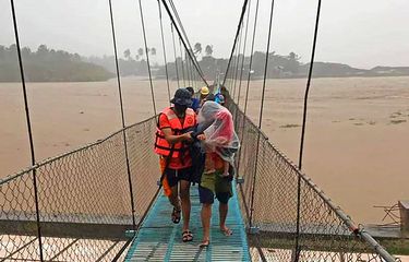 Tim penyelamat membantu warga menyeberangi jembatan saat mereka dievakuasi ke tempat yang lebih tinggi di Kota Tubay, Agusan del Norte, Filipina selatan pada Kamis (16/12/2021). Puluhan ribu orang sedang dievakuasi ke tempat yang aman di Filipina selatan dan tengah ketika Topan Rai menerjang Filipina.