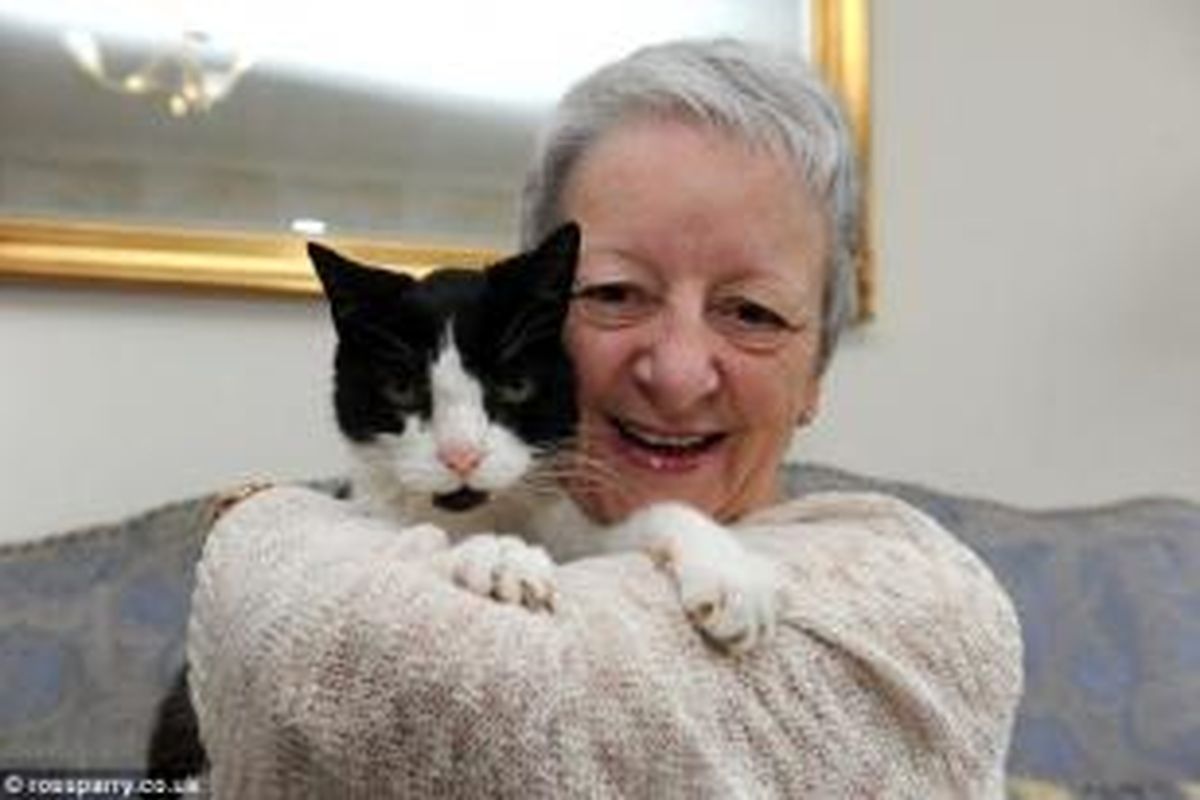Sue memeluk kucingnya Tom yang membantu deteksi kanker di lehernya.
