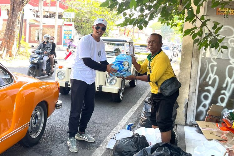 Salah satu anggota Volkswagen Jawa Timur membagikan sembako kepada masyarakat tidak mampu yang ditemui saat konvoi memperingati Hari Kemerdekaan RI ke-80 dan merayakan HUT Volkswagen Indonesia ke-32 di Surabaya, Sabtu (16/8/2025) siang.