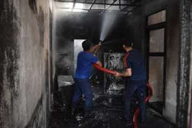 Dua petugas pemadam kebakaran Kota Baubau sedang berupaya memadamkan api yang telah menghanguskan tiga buah rumah, jumat (22/7/2016)