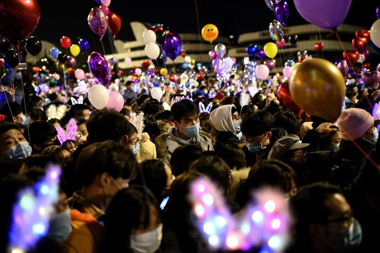 Orang-orang yang memakai masker wajah memadati jalan untuk menghitung mundur Tahun Baru di Wuhan di provinsi Hubei tengah China pada 31 Desember 2020.
