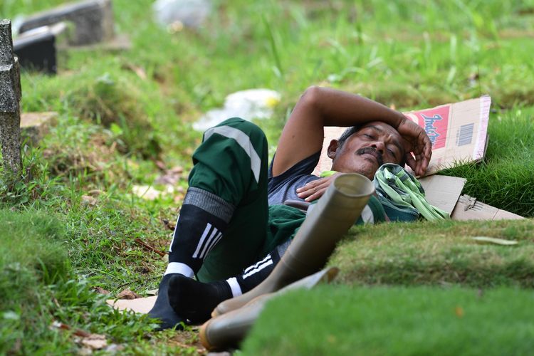 Foto yang diambil pada 6 Mei 2020, memperlihatkan Minar salah seorang penggali makam di pemakaman Pondok Ranggon, Jakarta Timur, sedang beristirahat. Pondok Ranggon merupakan salah satu dari dua pemakaman yang ditunjuk khusus untuk mengubur korban meninggal Covid-19 di Jakarta. AFP memberitakan para penggali makam bekerja 15 jam per hari, 7 hari per minggu, dengan gaji bulanan Rp 4,2 juta.