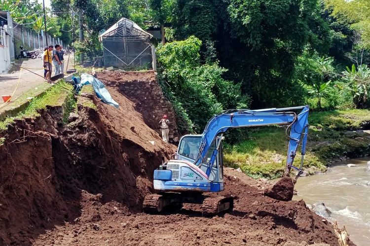 Alat berat sedang membuat galian untuk pondasi dalam pembangunan plengsengan yang ambrol di perumahan Sengkaling Residence yang berada di Jalan Ir Soekarno, Kota Batu.