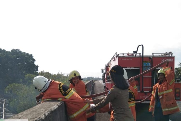 Petugas Damkar Kota Salatiga memadamkan api di bawah jembatan tol.