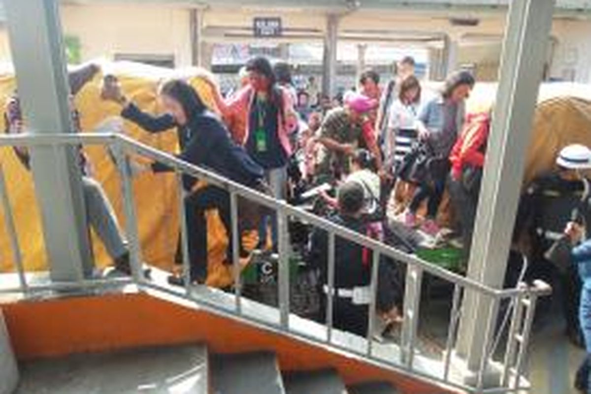 Sejumlah penumpang wanita tampak mencoba melewati gerbong kereta barang yang berhenti di Stasiun Depok, Jumat (26/9/2014) pagi. Posisi kereta barang yang sedang berhenti menghalangi jalur menuju ke peron sehingga menyebabkan para penumpang KRL mau tidak mau harus memanjat gerbong kereta.