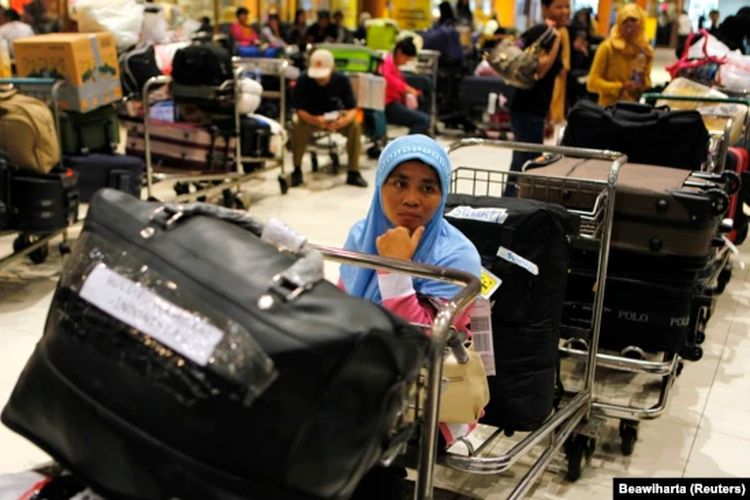 Seorang tenaga kerja perempuan Indonesia duduk di atas troli ketika menunggu berkas miliknya diperiksa saat tiba di Bandara Soekarno-Hatta.