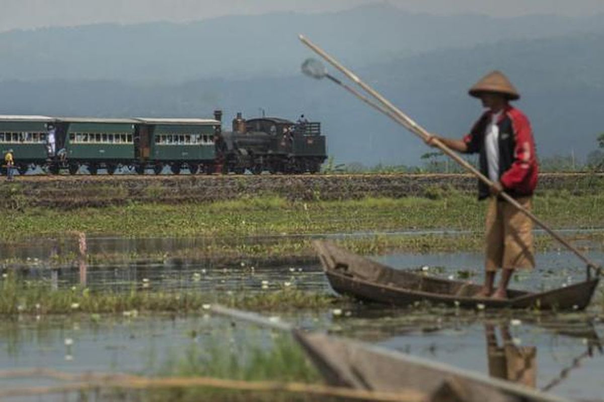 Lokomotif uap B 5112 yang melintasi Danau Rawa Pening di Kecamatan Bawen, Kabupaten Semarang, Jawa Tengah, menarik gerbong kereta wisata dari Stasiun Ambarawa menuju Stasiun Tuntang, Sabtu (24/9/2016). Lokomotif buatan pabrik Hannoversche Maschinenbau AG di Jerman tahun 1902 itu menjadi salah satu daya tarik wisata utama Museum Kereta Api Ambarawa. 