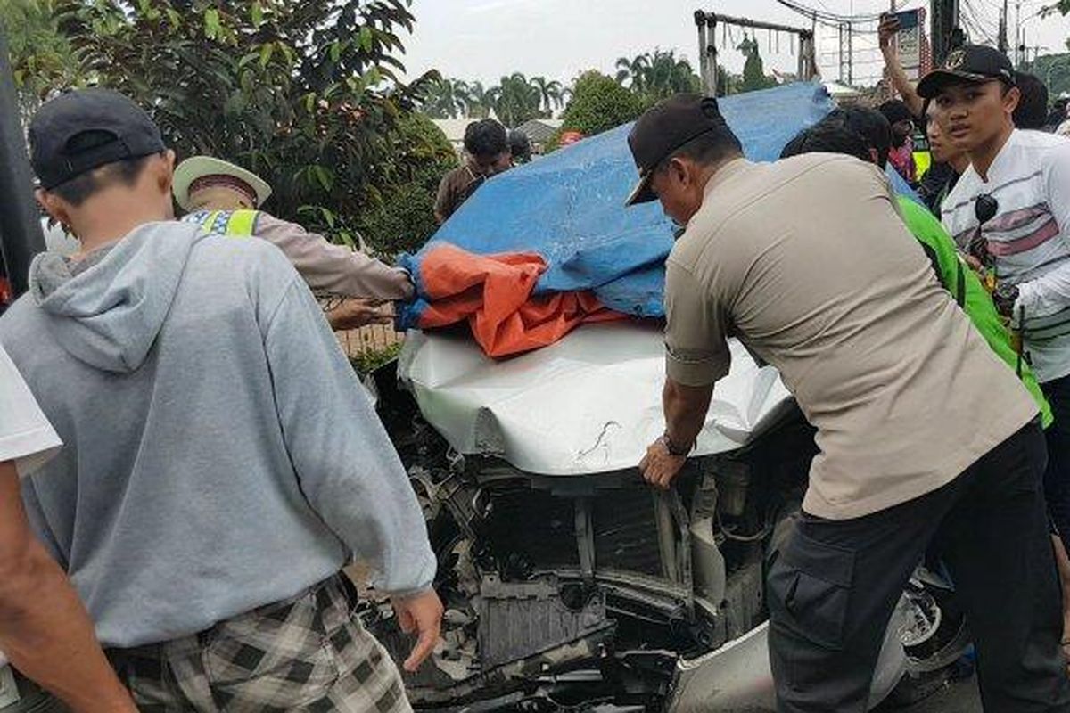 Polisi dengan warga sekitar mengevakuasi satu unit mobil Toyota Avanza yang terlibat kecelakaan maut. 
