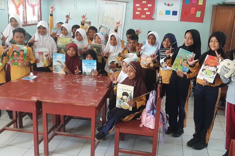 Anak-anak sekolah memegang buku bacaan bermutu dari Kemendikbud Ristek.